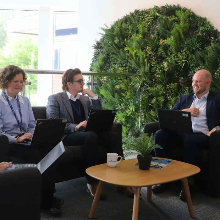 Invicta Law colleagues working on laptops around coffee table.