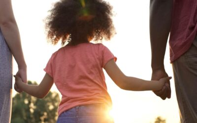 Close up of parents on either side of child holding hands